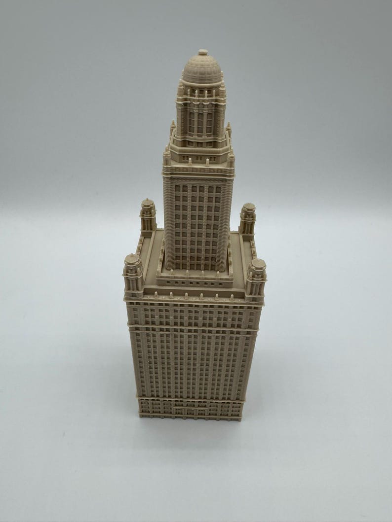 May include: A beige architectural model of a tall building with a detailed facade. The model features a rectangular base with a tower that has a domed top. The building has many windows and decorative elements.