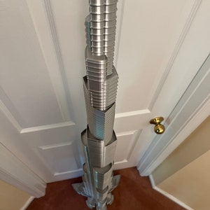May include: A silver 3D printed model of a skyscraper, viewed from directly above.