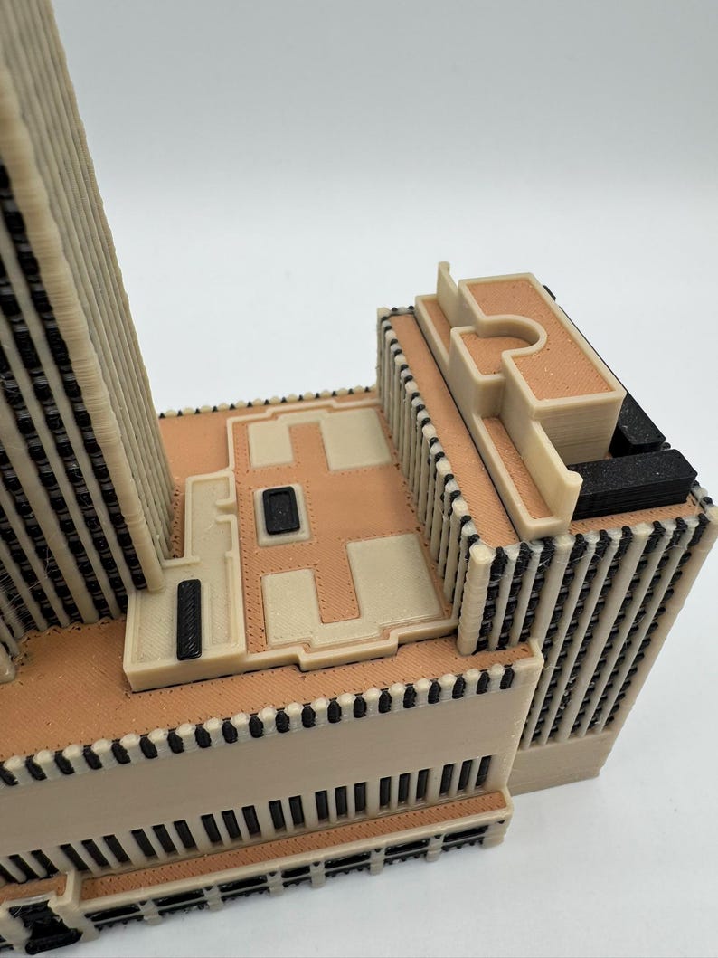 Puede incluir: Maqueta arquitect&oacute;nica detallada de un edificio, con una combinaci&oacute;n de colores beige y negro. El modelo presenta detalles intrincados, incluyendo l&iacute;neas verticales y patrones rectangulares, con un techo plano y m&uacute;ltiples niveles. El dise&ntilde;o es moderno y geom&eacute;trico.