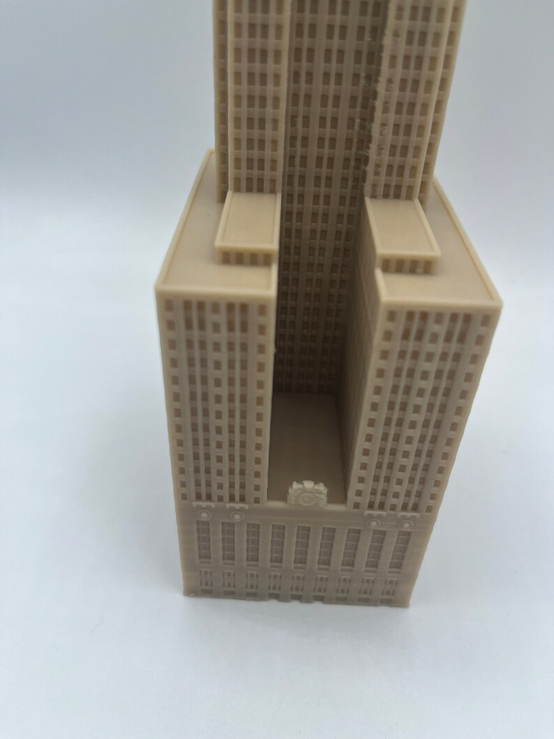 May include: A beige 3D printed model of a skyscraper with a clock face on the front.