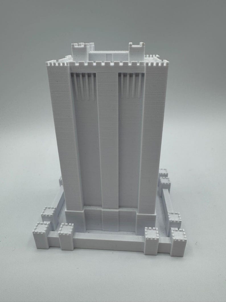 May include: White 3D printed model of a tall tower with crenellations and a square base.