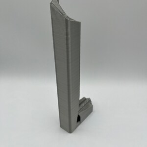 May include: A gray 3D printed model of a skyscraper with a unique, angular design.