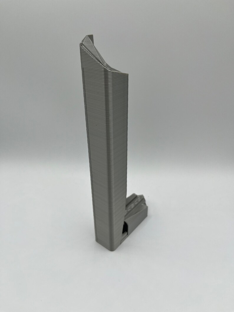 May include: A gray 3D printed model of a skyscraper with a unique, angular design.