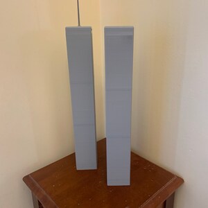 May include: Two grey miniature models of the World Trade Center towers on a wooden table.