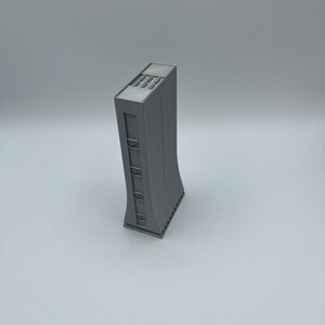May include: A gray 3D printed model of a tall building with a curved facade and a flat roof.