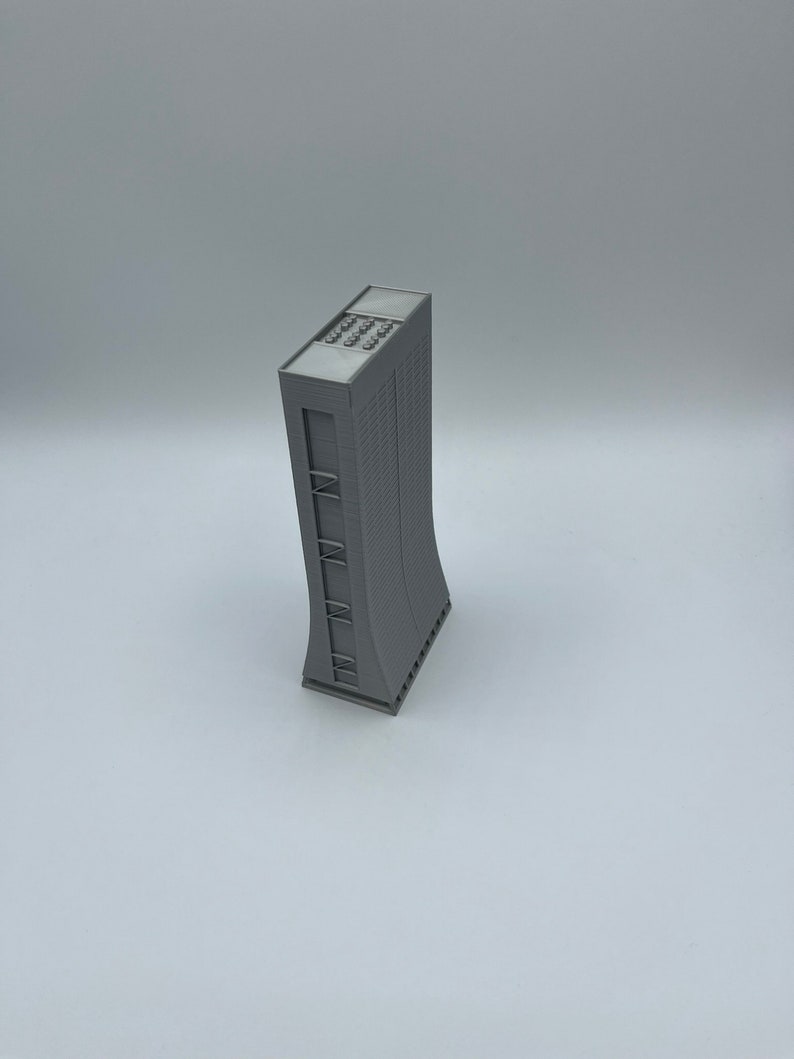 May include: A gray 3D printed model of a tall building with a curved facade and a flat roof.