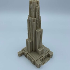 May include: A detailed 3D printed model of a tall building with a pointed roof and many windows. The model is beige in color and appears to be a replica of a famous landmark.