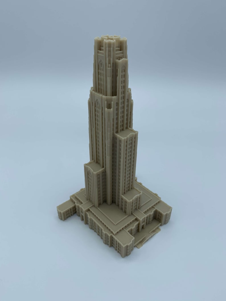 May include: A detailed 3D printed model of a tall building with a pointed roof and many windows. The model is beige in color and appears to be a replica of a famous landmark.