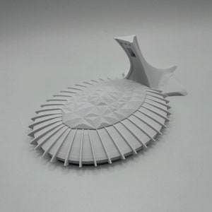 May include: A white 3D printed model of a futuristic building with a geometric design and a raised platform.