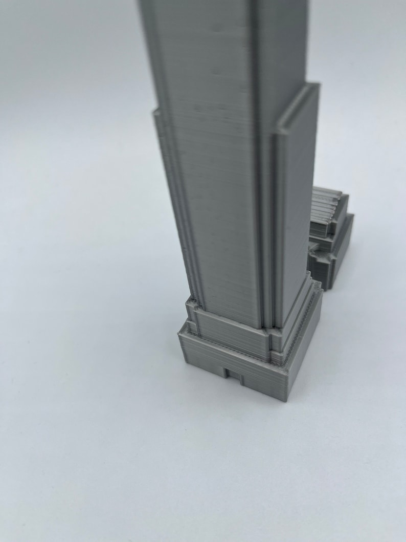 May include: A gray 3D printed model of a skyscraper.
