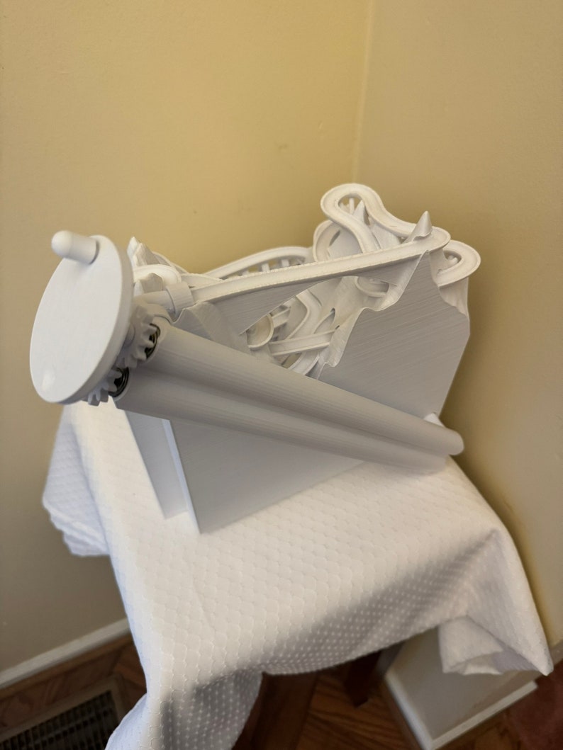 May include: White 3D printed marble run toy with a winding track and a crank to start the marbles rolling.