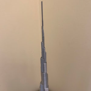 May include: A silver model of the Burj Khalifa, a skyscraper in Dubai, United Arab Emirates.