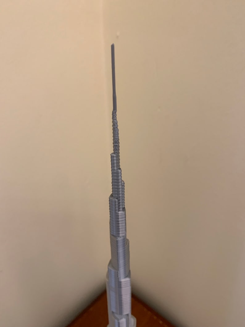 May include: A silver model of the Burj Khalifa, a skyscraper in Dubai, United Arab Emirates.