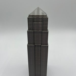 Peut inclure: Mod&egrave;le 3D imprim&eacute; en gris d'un gratte-ciel avec un toit pointu.