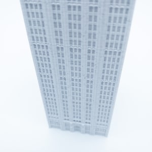 K&ouml;nnte beinhalten: Ein wei&szlig;es 3D-gedrucktes Modell eines hohen Geb&auml;udes mit vielen Fenstern.