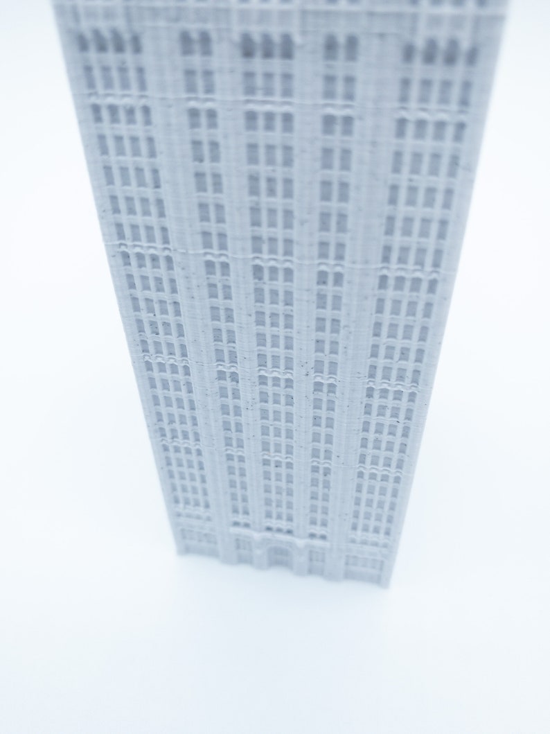 K&ouml;nnte beinhalten: Ein wei&szlig;es 3D-gedrucktes Modell eines hohen Geb&auml;udes mit vielen Fenstern.