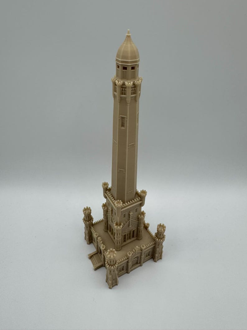 May include: A beige 3D-printed model of a tall tower with a domed top and multiple levels. The tower has a rectangular base with decorative elements, including small turrets at each corner. The model is detailed and stands on a white surface.