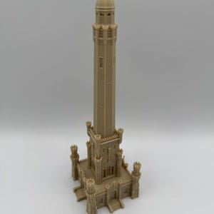 May include: A beige 3D-printed model of a tall, ornate tower. The tower has a detailed architectural design with multiple levels, windows, and decorative elements. The model is standing on a square base with four corner turrets.