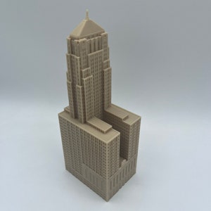 May include: A detailed model of a tall, beige building with a pointed roof and many windows. The model is made of plastic and is about 10 inches tall.