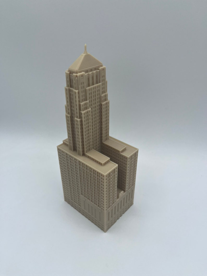 May include: A detailed model of a tall, beige building with a pointed roof and many windows. The model is made of plastic and is about 10 inches tall.