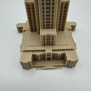 May include: A beige 3D printed model of a tall building with many windows and a detailed facade.