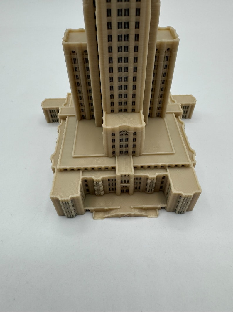 May include: A beige 3D printed model of a tall building with many windows and a detailed facade.