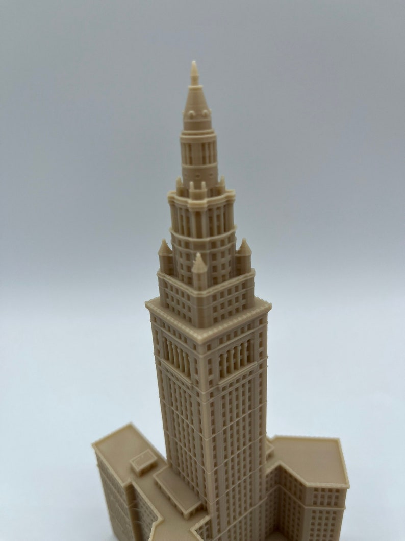 May include: A detailed model of a tall, beige building with a pointed spire. The building has many windows and intricate details.