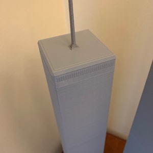 May include: A close-up of a grey 3D printed model of a skyscraper with a silver antenna on top.