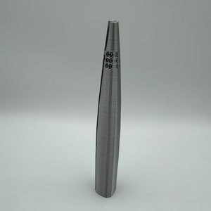 May include: A silver metal tweezers with a textured surface and a decorative design at the top.