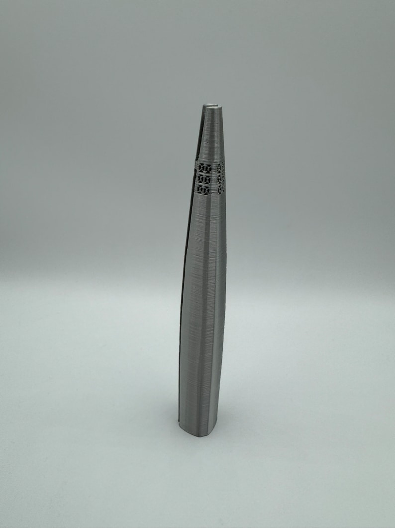May include: A silver metal tweezers with a textured surface and a decorative design at the top.