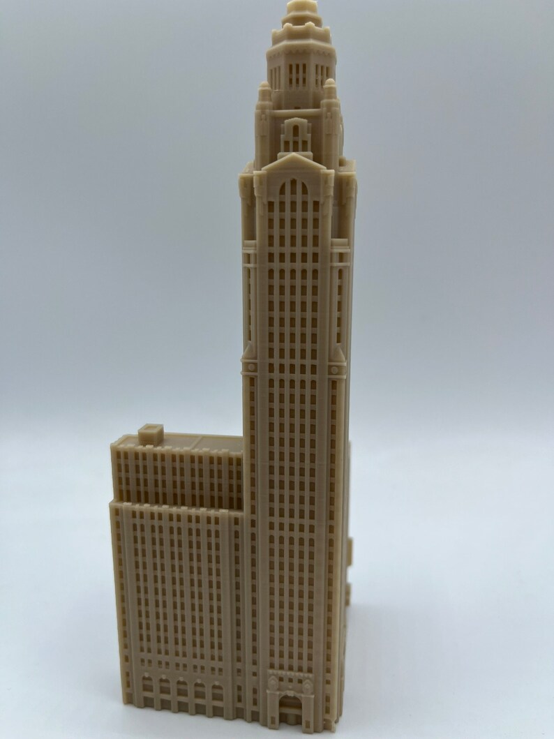 May include: A beige 3D printed model of a tall skyscraper with a decorative top and many windows.