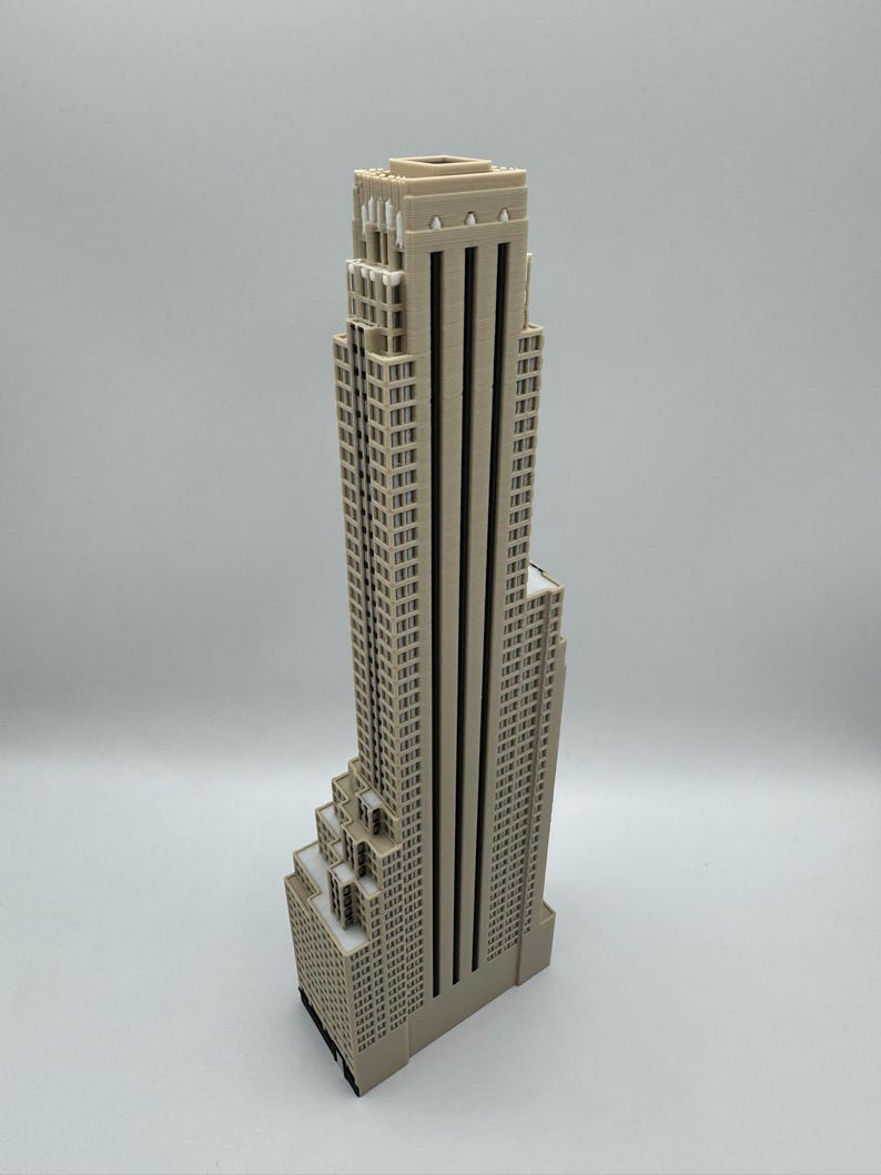 May include: A beige architectural model of a skyscraper. The building has a stepped design with multiple levels and a flat roof. The model is made of a light-colored material and stands tall against a plain background.