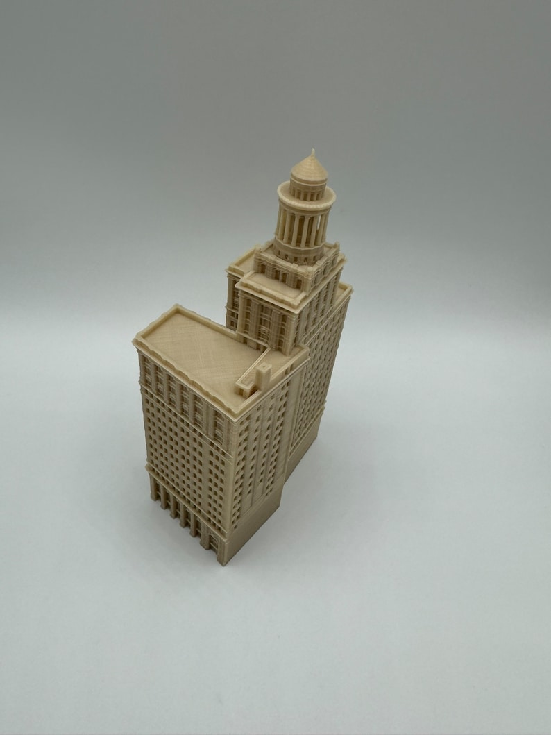 May include: A beige 3D printed model of a tall building with a domed roof. The building has many windows and a detailed facade.