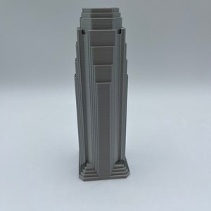May include: A gray 3D printed model of a skyscraper with a stepped design.