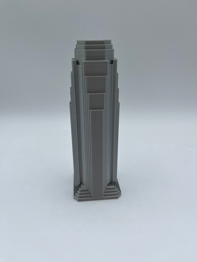 May include: A gray 3D printed model of a skyscraper with a stepped design.