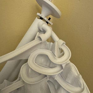May include: White 3D printed sculpture of a person with a large hat and a complex, winding track system. The track system is made of white plastic and appears to be a marble run.