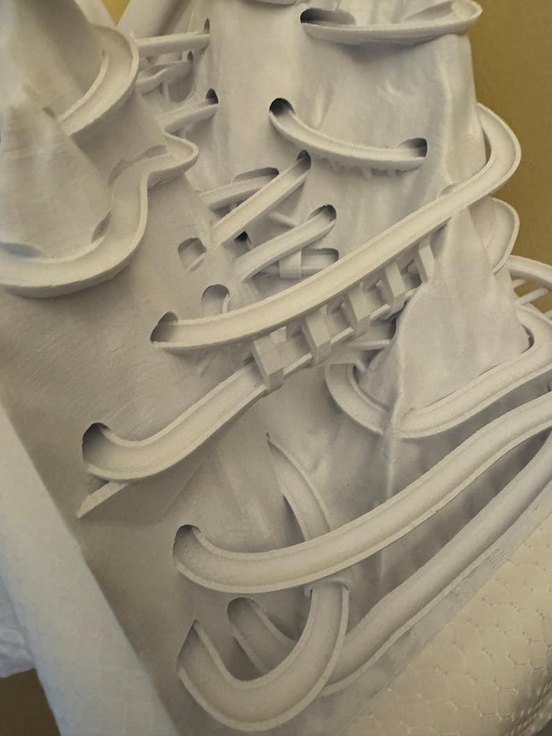 May include: White 3D printed sculpture with a complex, intricate design of interconnected curves and loops.