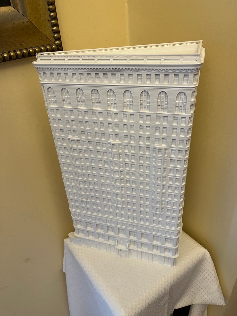 Puede incluir: Un modelo 3D impreso en blanco de un edificio alto con muchas ventanas. El edificio tiene una fachada detallada con arcos y molduras decorativas.