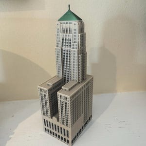 Peut inclure: Maquette détaillée d'un gratte-ciel avec un toit vert et une façade gris clair. Le bâtiment comporte plusieurs étages et fenêtres, et est une réplique miniature d'un célèbre monument architectural.