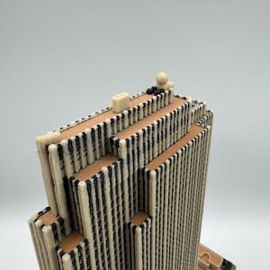 Puede incluir: Maqueta arquitect&oacute;nica detallada de un rascacielos. El edificio presenta una fachada color crema con detalles negros verticales y bandas horizontales de color marr&oacute;n. El modelo tiene un techo plano con peque&ntilde;os detalles arquitect&oacute;nicos.