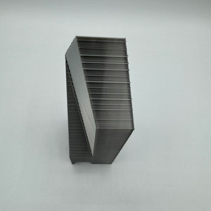 May include: A gray, 3D printed object with a geometric shape. The object is made up of many layers, creating a textured surface.