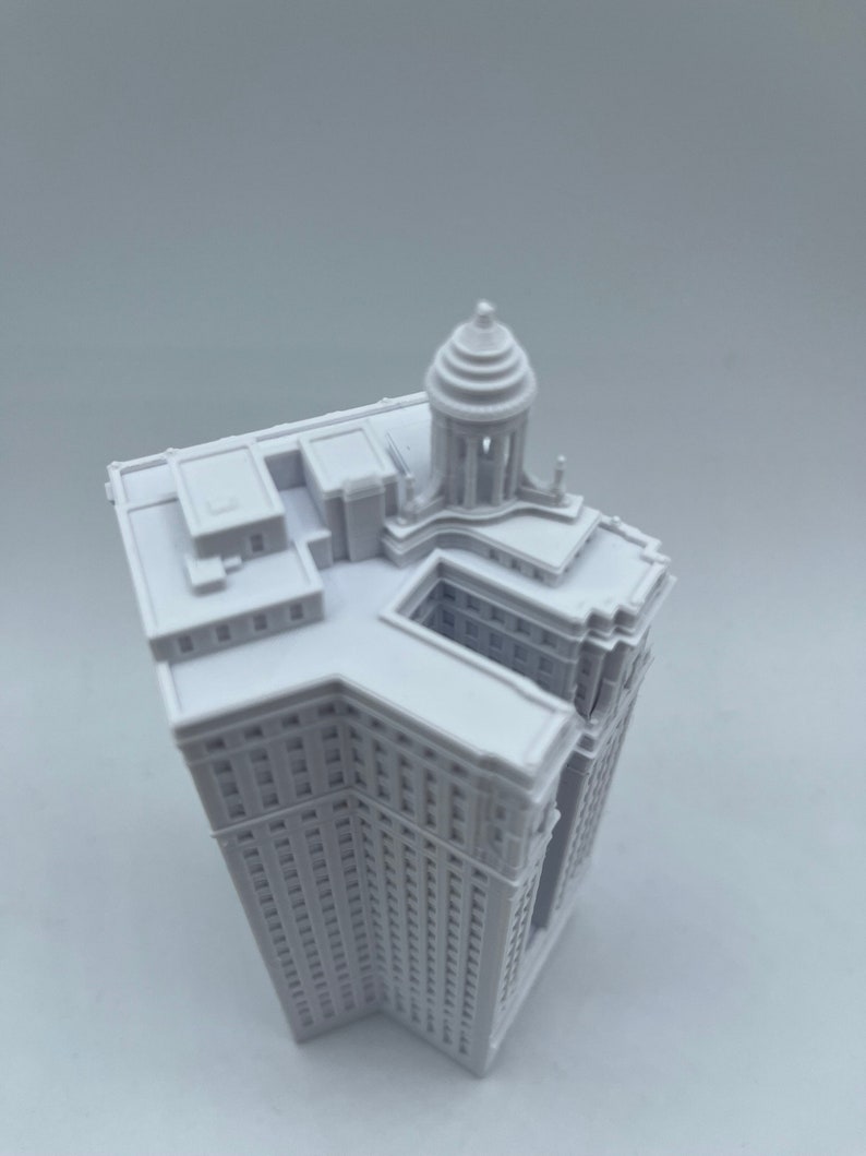 Op de afbeelding: Wit 3D-geprint model van een hoog gebouw met een koepelvormig dak.