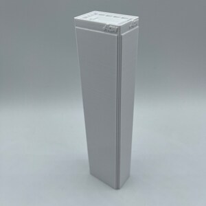 K&ouml;nnte beinhalten: Ein wei&szlig;es 3D-gedrucktes Modell eines Wolkenkratzers mit dem Text "4CM" auf der Oberseite.