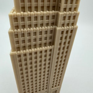 Pu&ograve; includere: Un modello 3D stampato in beige di un edificio alto con molte finestre e una facciata dettagliata.