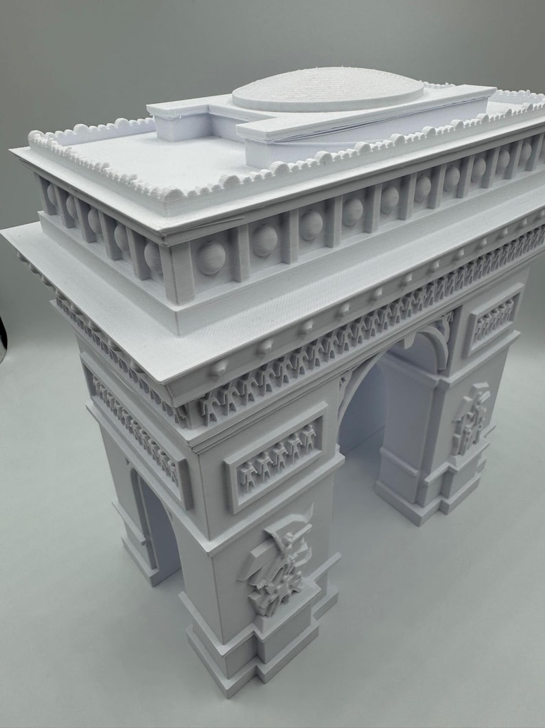 Może przedstawiać: Biały model Łuku Triumfalnego, znanego paryskiego zabytku. Model posiada szczeg&oacute;łowe rzeźbienia, łuki i kopulasty dach. Miniaturowa replika z misternymi detalami.