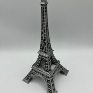 May include: A gray metal model of the Eiffel Tower. The model is detailed and has a realistic design.