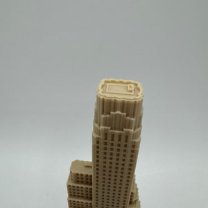 May include: A beige 3D printed model of a skyscraper with a flat roof and many windows.