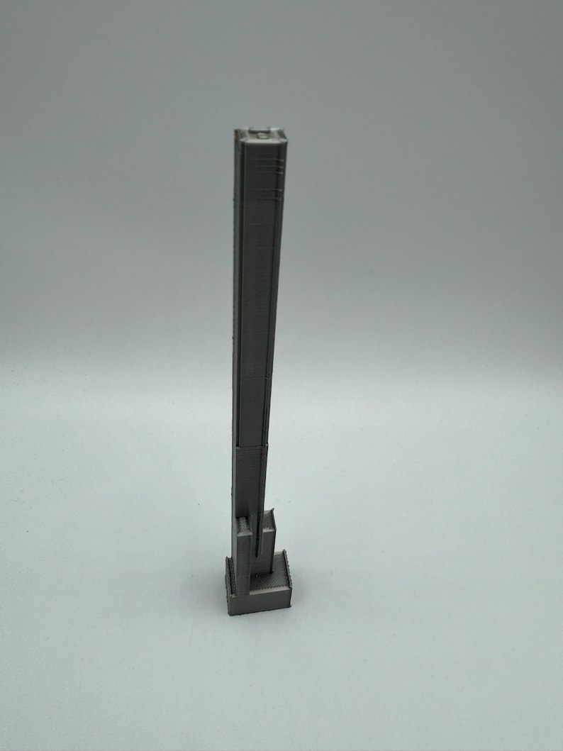 Op de afbeelding: Een 3D-geprint model van een hoog, slank gebouw met een rechthoekige basis. Het gebouw is grijs en heeft een getextureerd oppervlak.