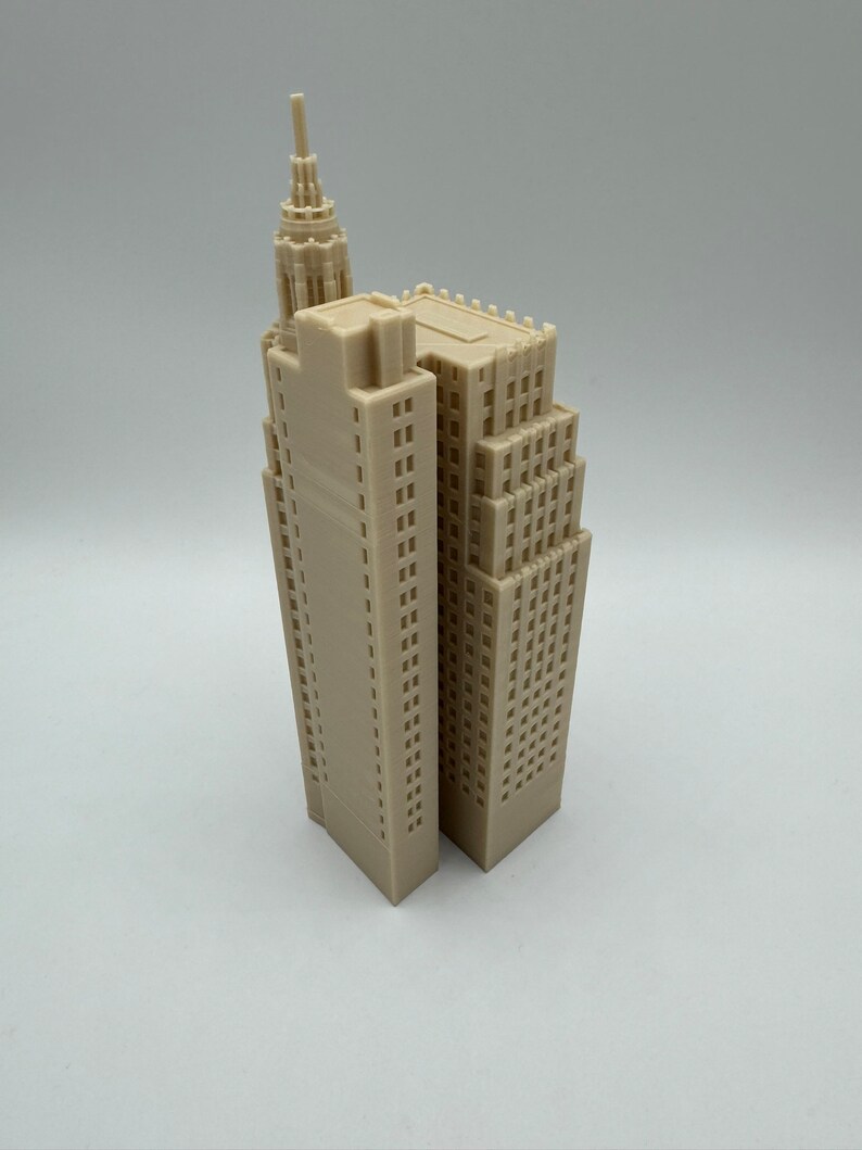 Pu&ograve; includere: Un modello di grattacielo beige stampato in 3D con un tetto a punta e molte finestre.