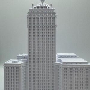 Puede incluir: Maqueta arquitect&oacute;nica gris claro de un rascacielos. El edificio presenta m&uacute;ltiples pisos con numerosas ventanas, una corona detallada y varias alas inferiores. El modelo es una representaci&oacute;n de un dise&ntilde;o de edificio cl&aacute;sico.